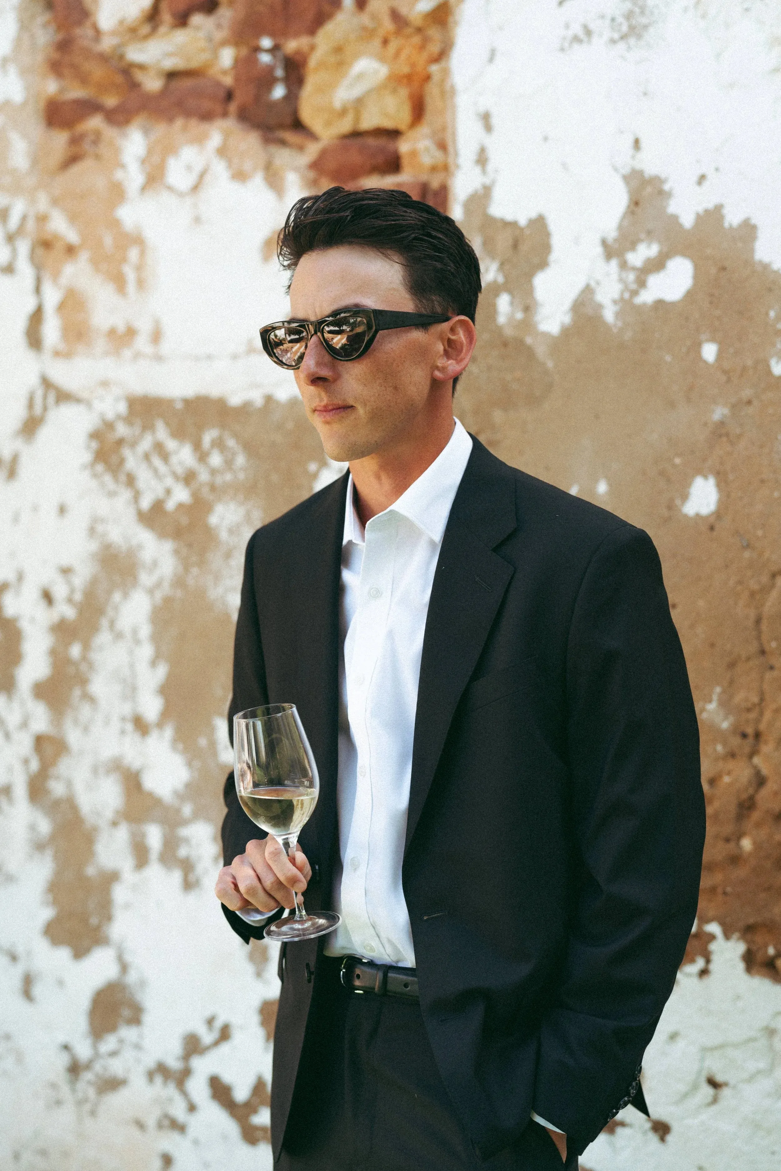 Max with a glass of wine against a peeling wall