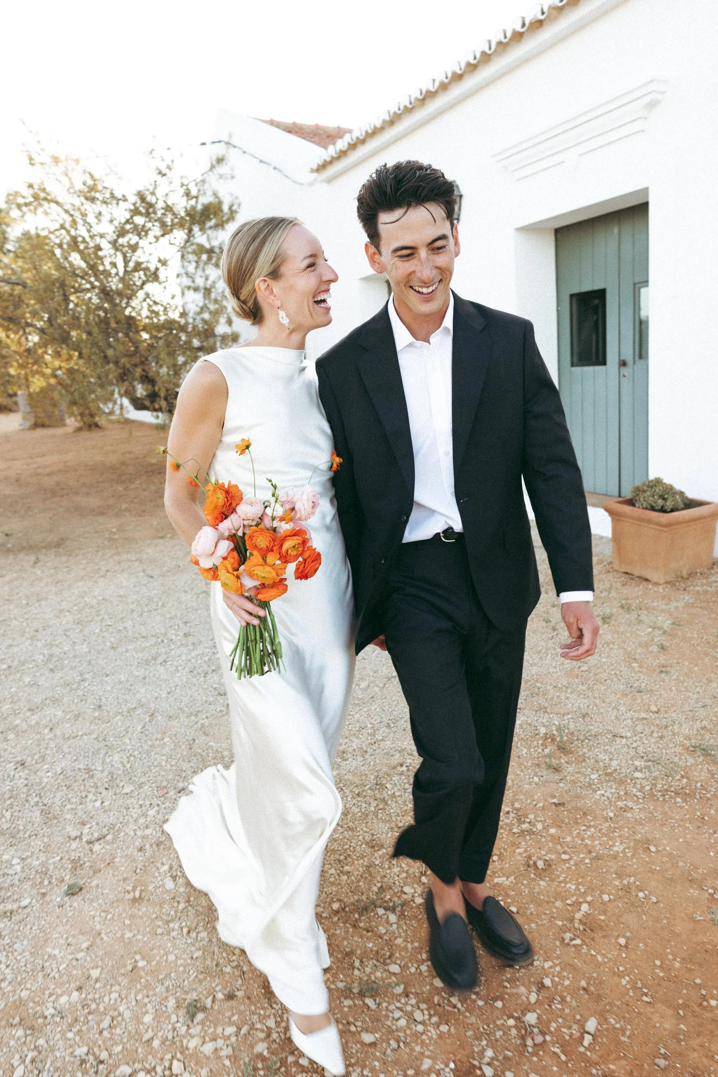 Lindsey and Max walking out of a whitewashed farmhouse